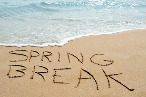 The text spring break written in the sand of a beach.